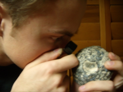 holding rock close to hand lens